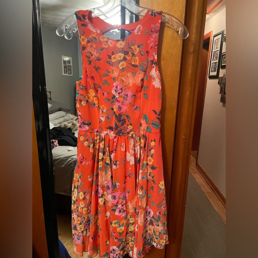 Orange halter dress with light orange, yellow and white floral pattern.